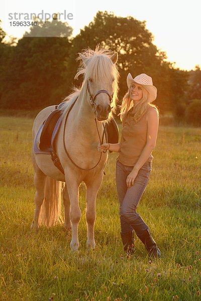 Lächelnde Frau mit Pferd auf einer Wiese