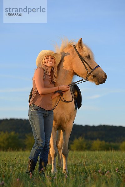 Lächelnde Frau mit Pferd auf einer Wiese