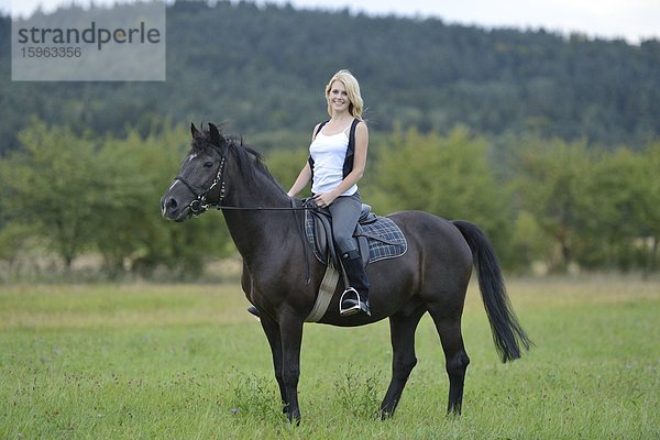 Lächelnde Frau sitzt auf einem Pferd