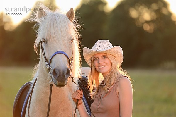 Lächelnde Frau mit Pferd auf einer Wiese  Portrait