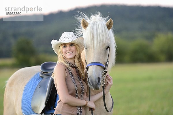 Lächelnde Frau mit Pferd auf einer Wiese