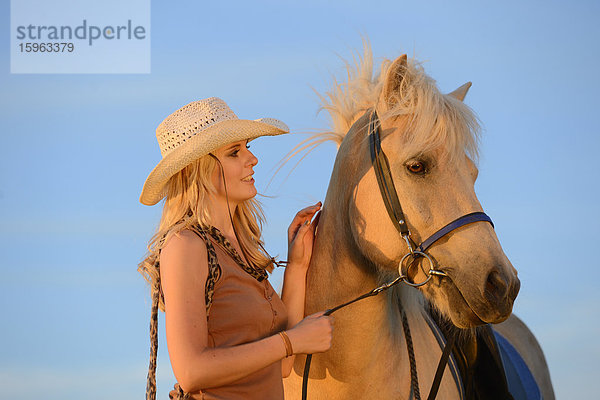 Lächelnde Frau mit Pferd unter blauem Himmel