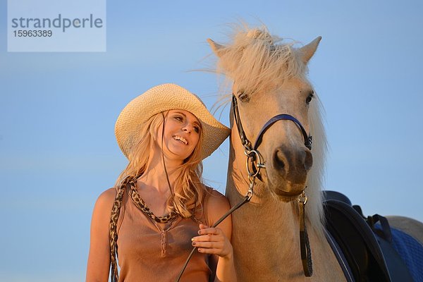 Lächelnde Frau mit Pferd unter blauem Himmel