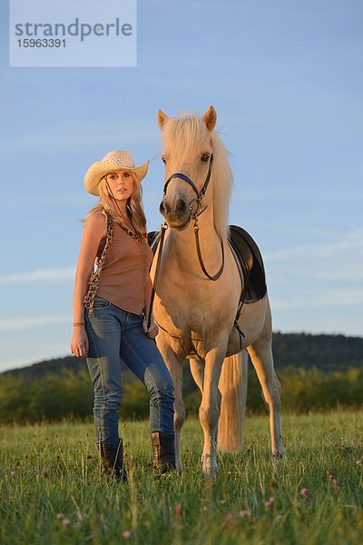 Junge Frau mit Pferd auf einer Wiese