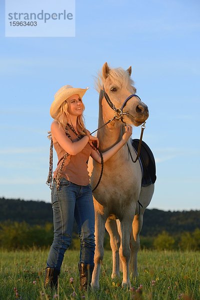 Lächelnde Frau mit Pferd auf einer Wiese