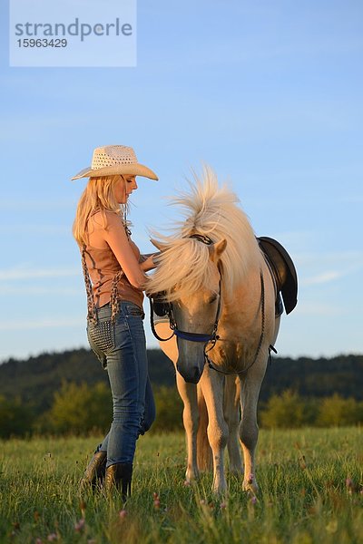 Junge Frau mit Pferd auf einer Wiese