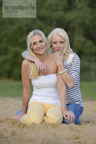 Zwei fröhliche blonde junge Frauen am Sandstrand