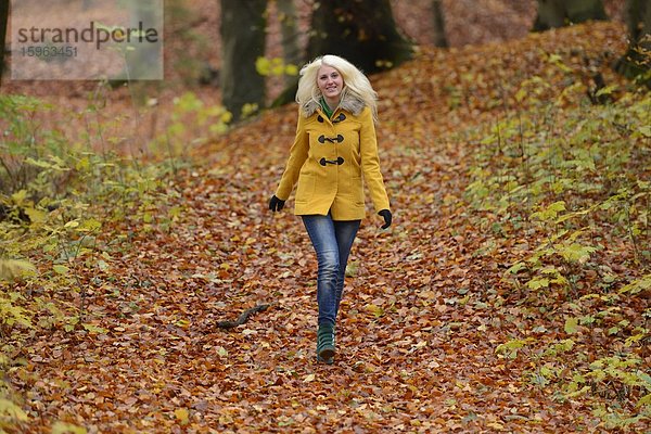 Fröhliche blonde junge Frau im Wald
