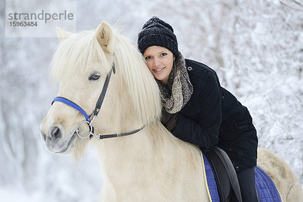 Junge Frau auf Pferd im Schnee