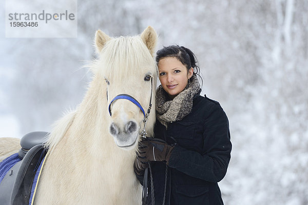 Junge Frau mit Pferd im Schnee