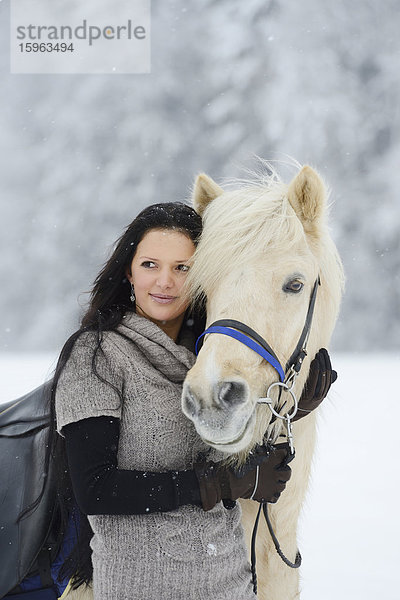 Junge Frau mit Pferd im Schnee