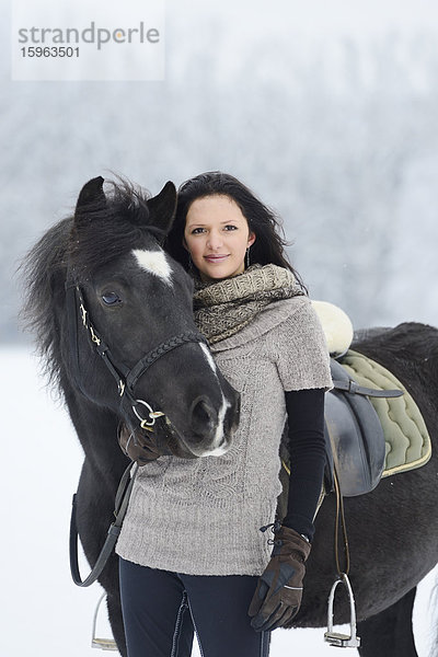 Junge Frau mit Pferd im Schnee