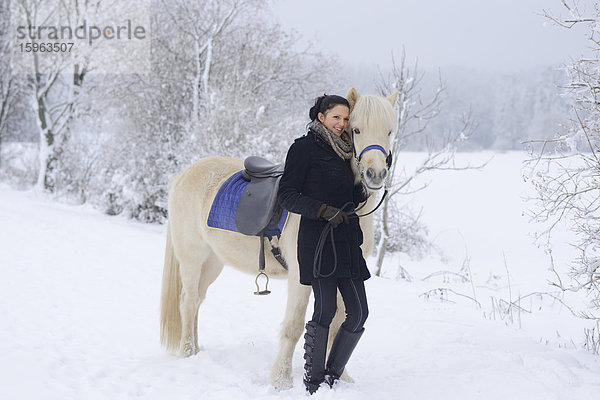 Junge Frau mit Pferd im Schnee