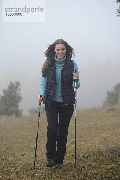 Brünette junge Frau macht Nordic Walking