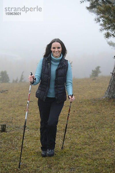 Brünette junge Frau macht Nordic Walking