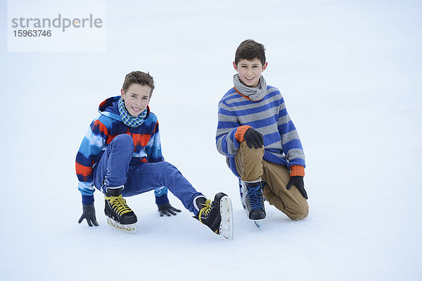 Zwei Jungen mit Schlittschuhen auf einem gefrorenen See