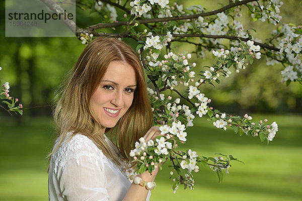 Junge Frau an einem blühenden Apfelbaum  Portrait