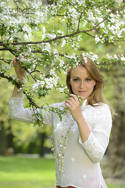 Junge Frau an einem blühenden Apfelbaum  Portrait