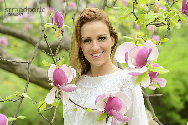 Junge Frau an einer blühenden Magnolie  Portrait