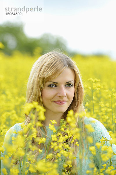 Blonde junge Frau in blühendem Rapsfeld