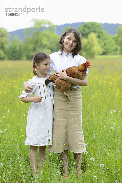 Zwei Schwestern mit einem Huhn