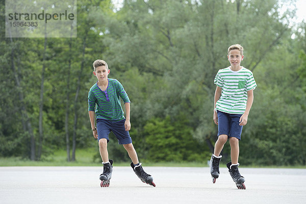 Zwei Jungen mit Inline-Skates auf einem Sportplatz