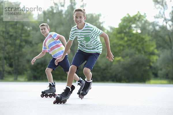 Zwei Jungen mit Inline-Skates auf einem Sportplatz