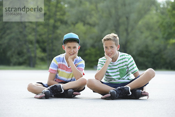 Zwei Jungen mit Inline-Skates auf einem Sportplatz