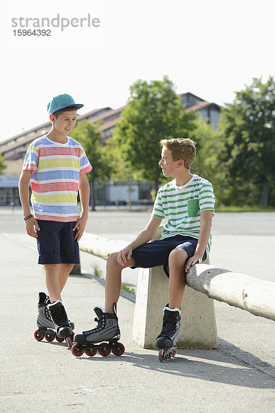 Zwei Jungen mit Inline-Skates auf einem Sportplatz