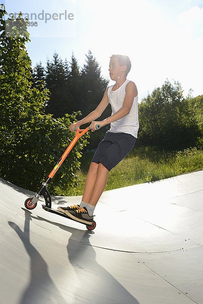 Junge mit Kickboard in einem Skatepark