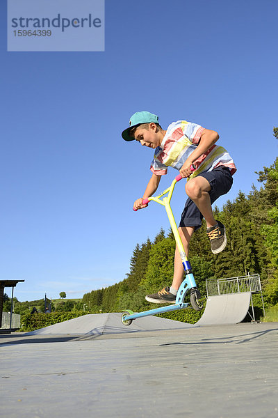 Junge mit Kickboard in einem Skatepark