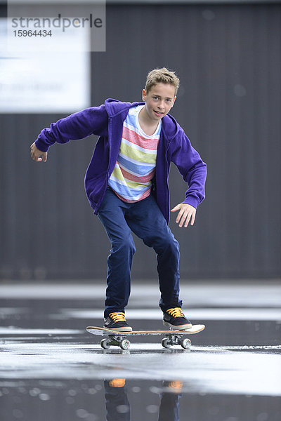 Junge mit Skateboard an einem regnerischen Tag