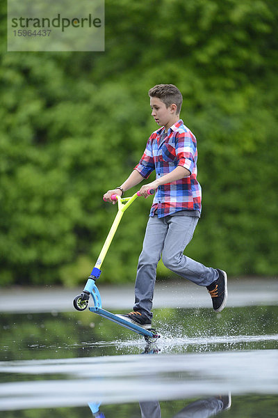 Junge mit Kickboard an einem regnerischen Tag