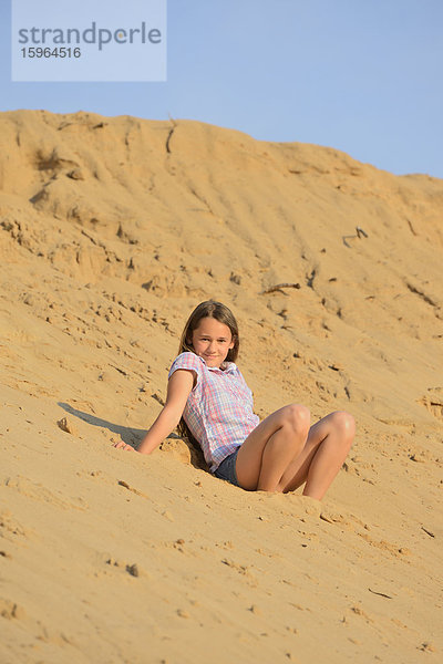 Mädchen sitzt am Sandstrand