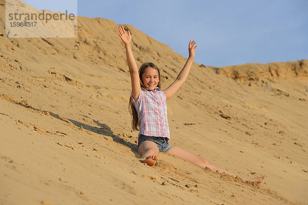 Mädchen sitzt am Sandstrand