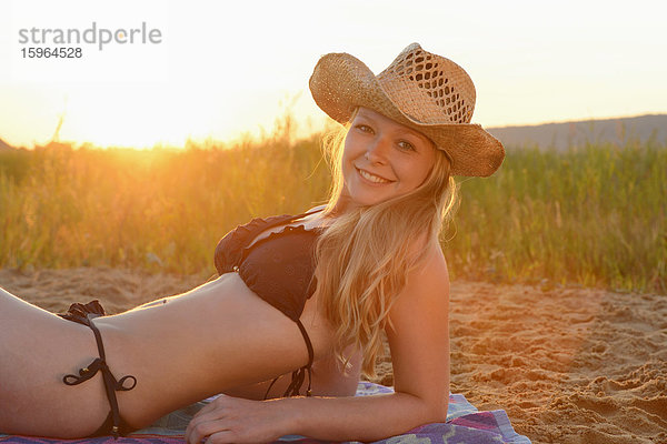 Junge Frau liegt im Bikini am Strand