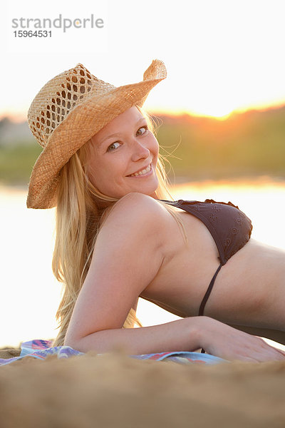 Junge Frau liegt im Bikini am Strand