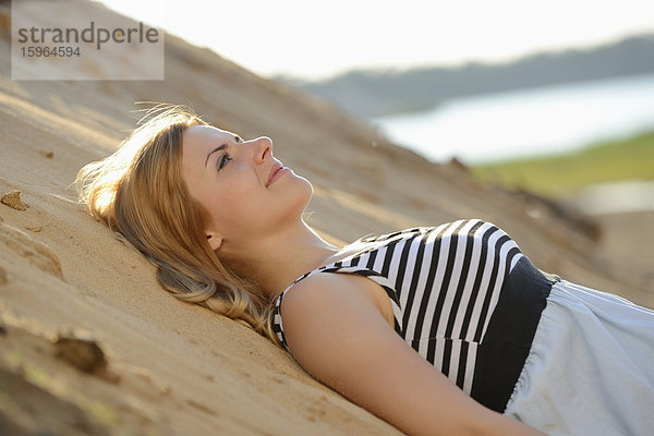 Junge Frau im Kleid liegt am Strand