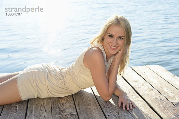 Junge blonde Frau auf einem Steg an einem See  Steiermark  Österreich