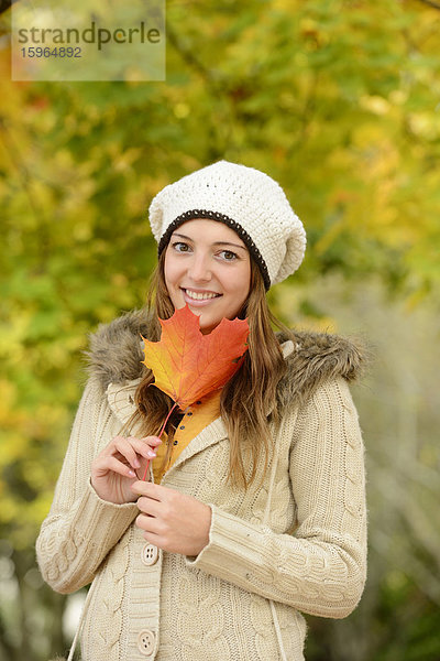 Lächelnde junge Frau mit Herbstblatt  Portrait