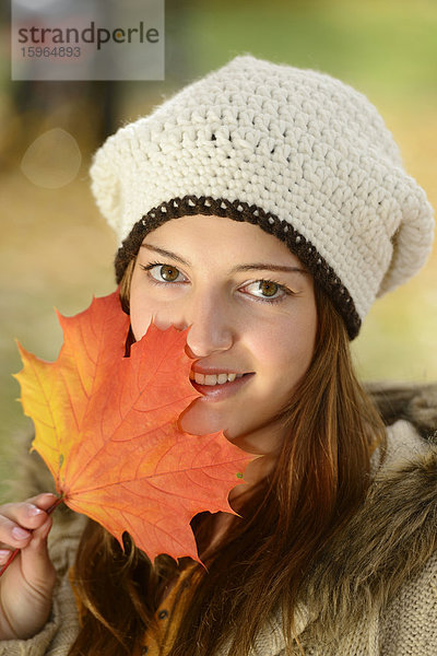 Lächelnde junge Frau mit Herbstblatt  Portrait