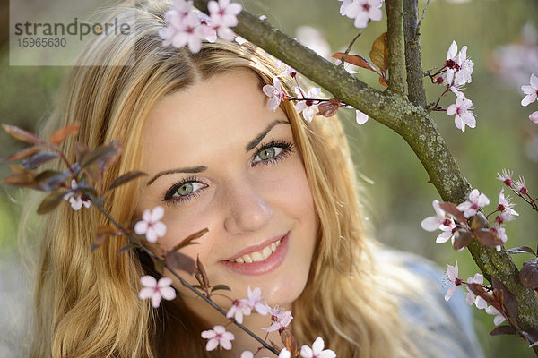 Junge Frau an blühendem Kirschbaum  Portrait