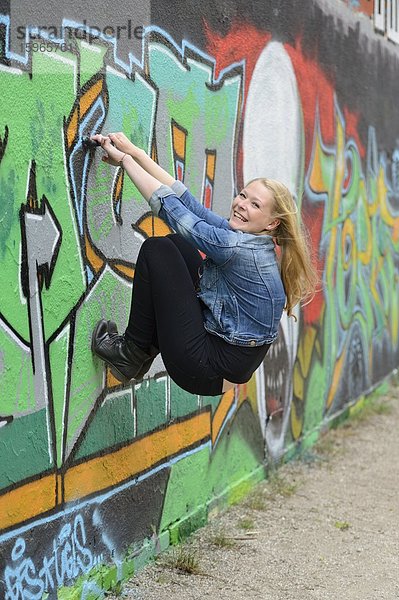 Junge Frau an einer Graffitiwand  Nürnberg  Bayern  Deutschland  Europa