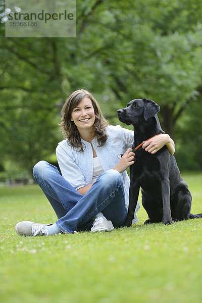 Frau mit einem schwarzen Labrador auf einer Wiese  Bayern  Deutschland  Europa