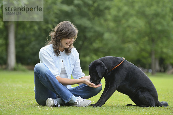 Frau mit einem schwarzen Labrador auf einer Wiese  Bayern  Deutschland  Europa