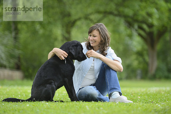 Frau mit einem schwarzen Labrador auf einer Wiese  Bayern  Deutschland  Europa