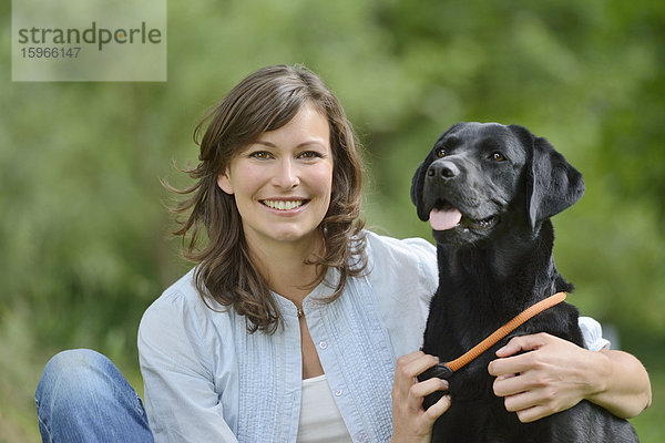 Frau mit einem schwarzen Labrador auf einer Wiese  Bayern  Deutschland  Europa