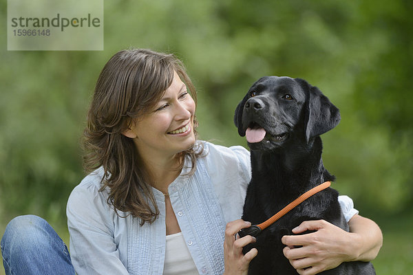 Frau mit einem schwarzen Labrador auf einer Wiese  Bayern  Deutschland  Europa