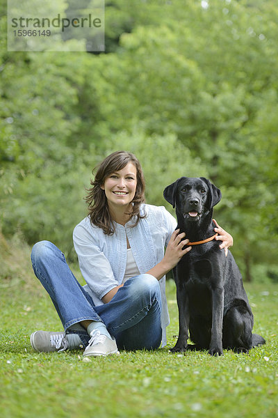 Frau mit einem schwarzen Labrador auf einer Wiese  Bayern  Deutschland  Europa