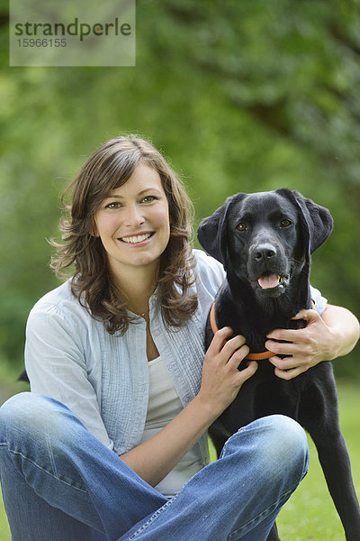 Frau mit einem schwarzen Labrador auf einer Wiese  Bayern  Deutschland  Europa